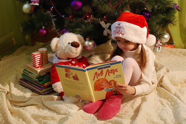 holčička si čte knížku u vánočního stromu